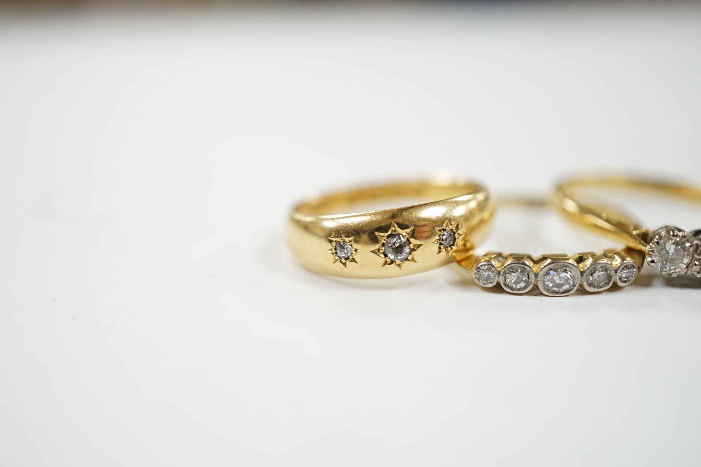 A late Victorian 18ct gold and gypsy set three stone diamond chip ring and two other 18ct and diamond set rings, three stone and five stone